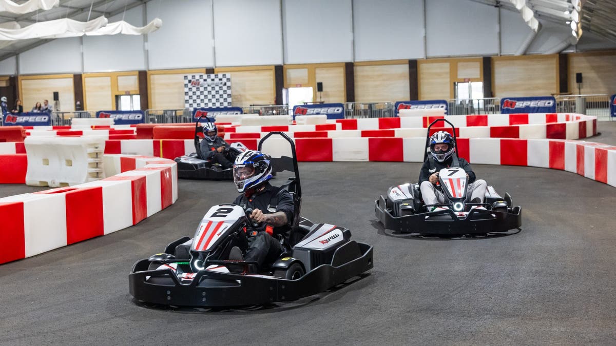 Drivers racing in go karts on a track.