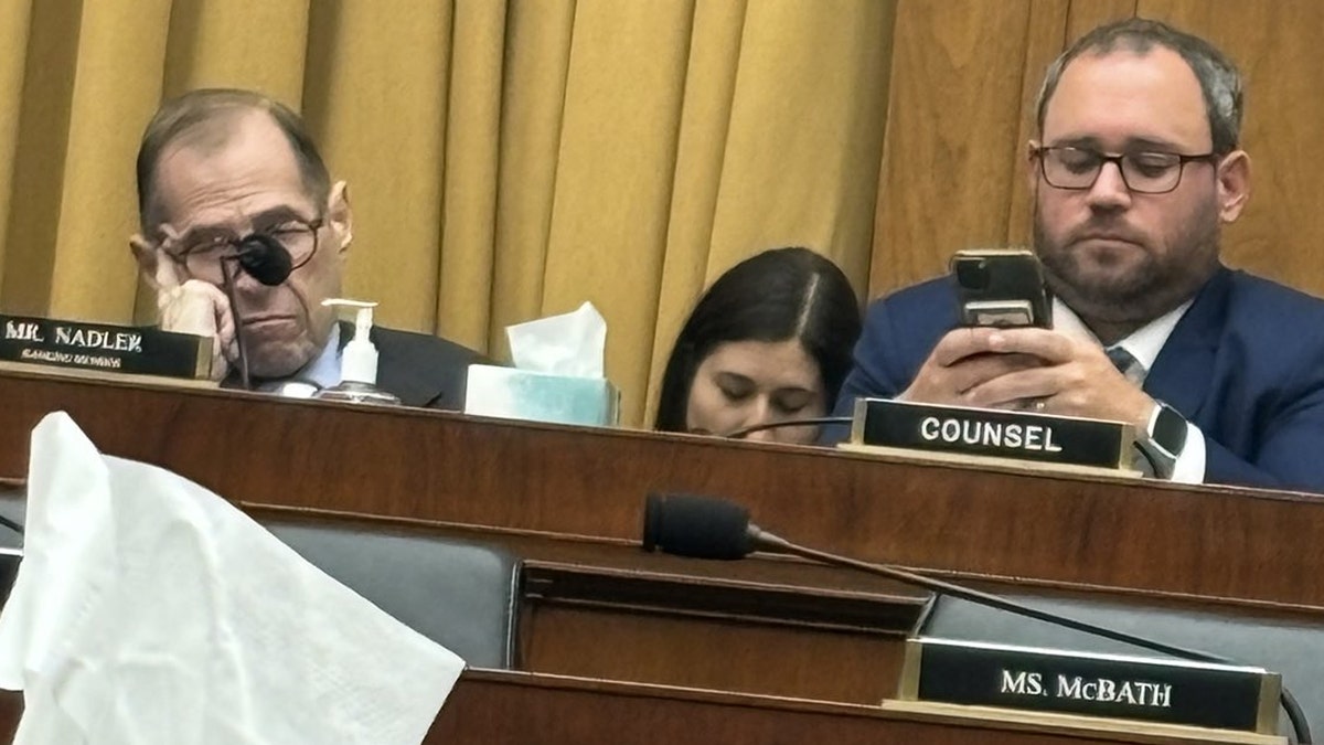 Rep Nadler clsoes his eyes as an aide looks at a cellphone