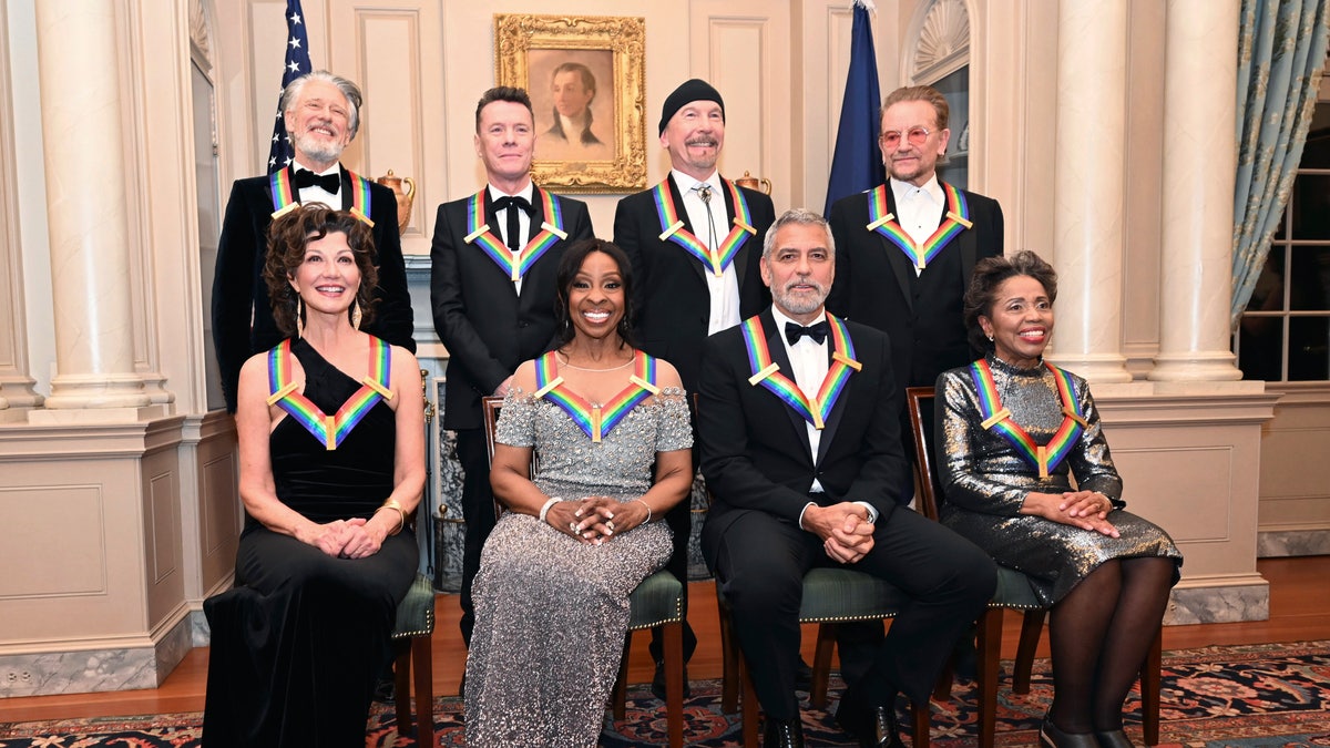 2022 Kennedy Center Honorees front row: Amy Grant in black, Gladys Knight in a sparkly dress, George Clooney in a tuxedo, Tania León in a shorter sparkly dress and back row: members of U2 Adam Clayton, Larry Mullen Jr. The Edge, and Bono all in tuxedos