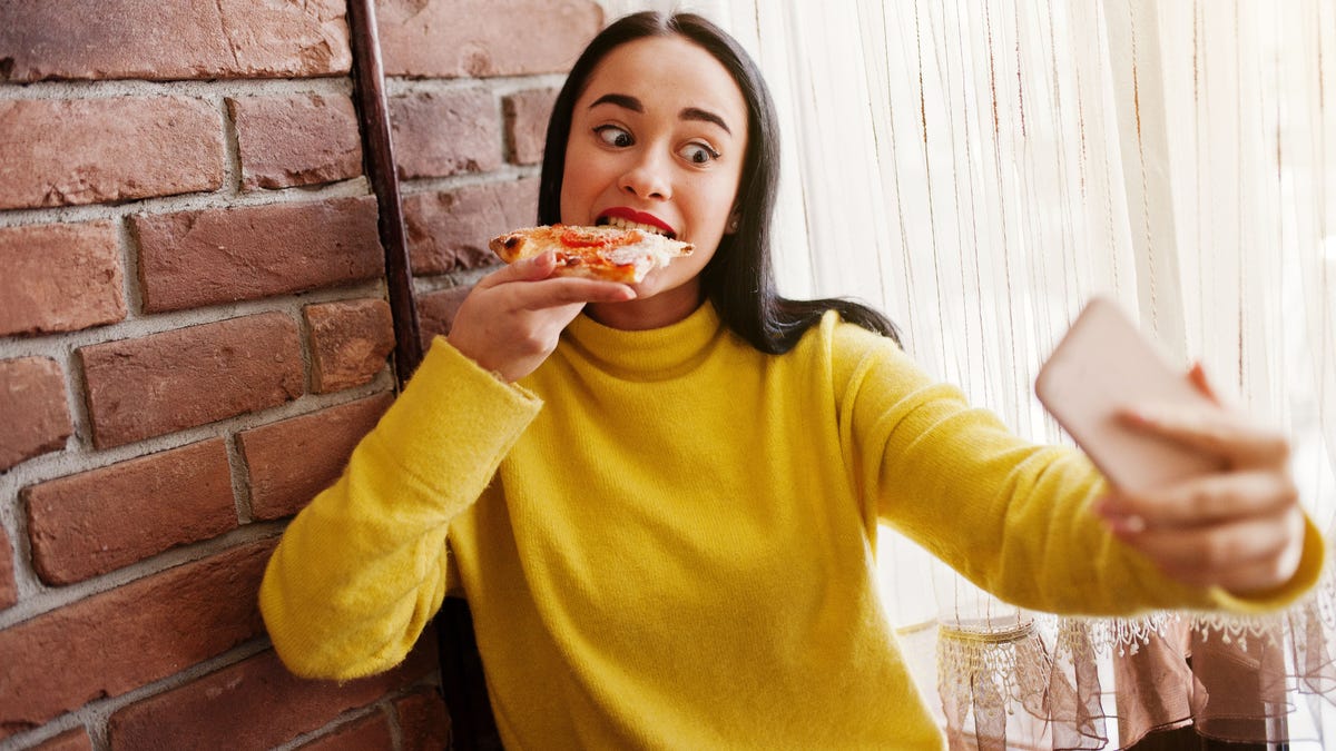 Woman takes a selfie while eating pizza