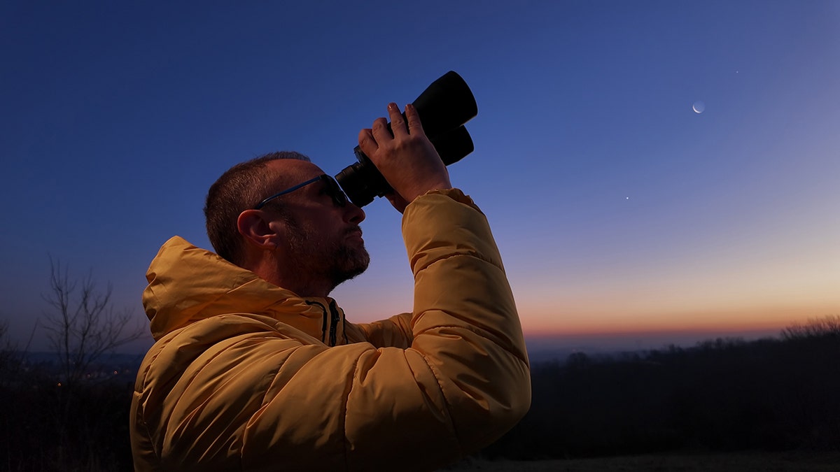 man looking through binocular