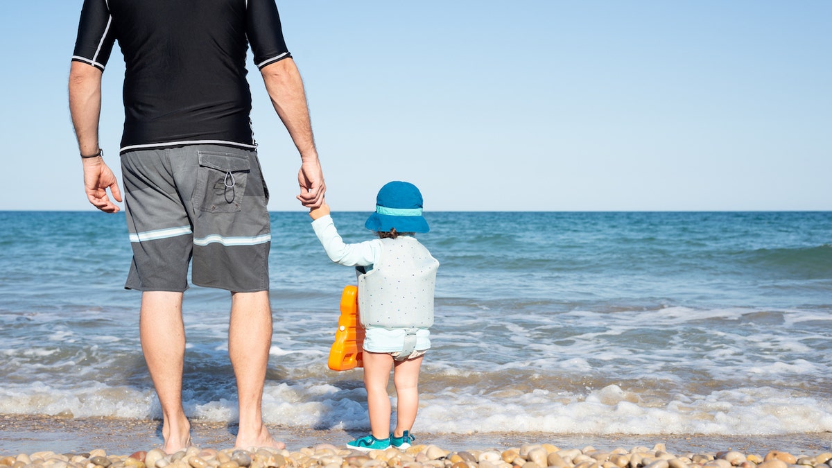 Father walks on a beach with baby 