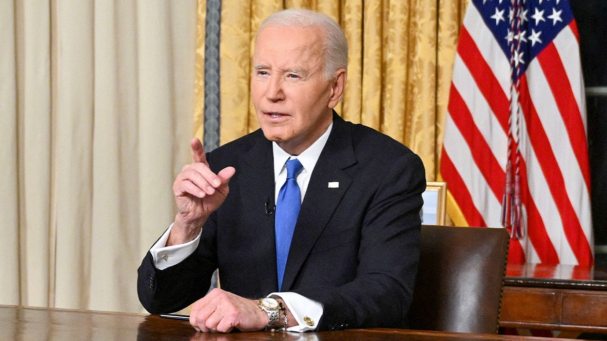 President Biden sits behind the desk in the Oval Office