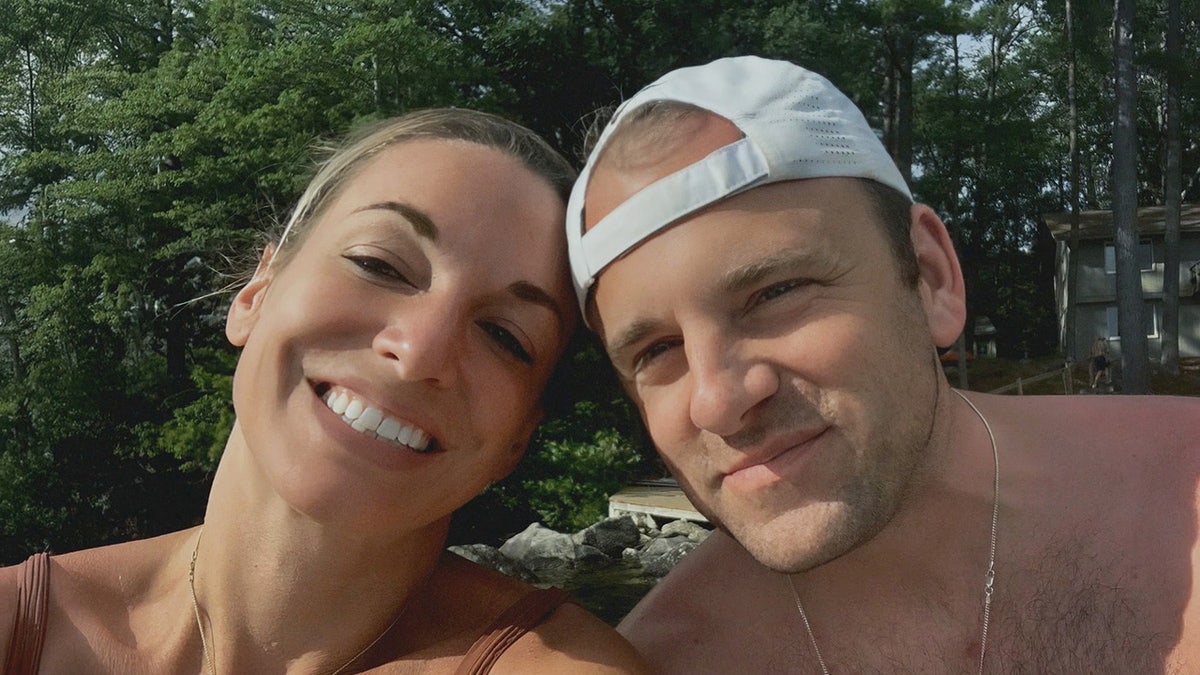 A close-up of Karen Read smiling next to John O'Keefe wearing a white backwards hat.