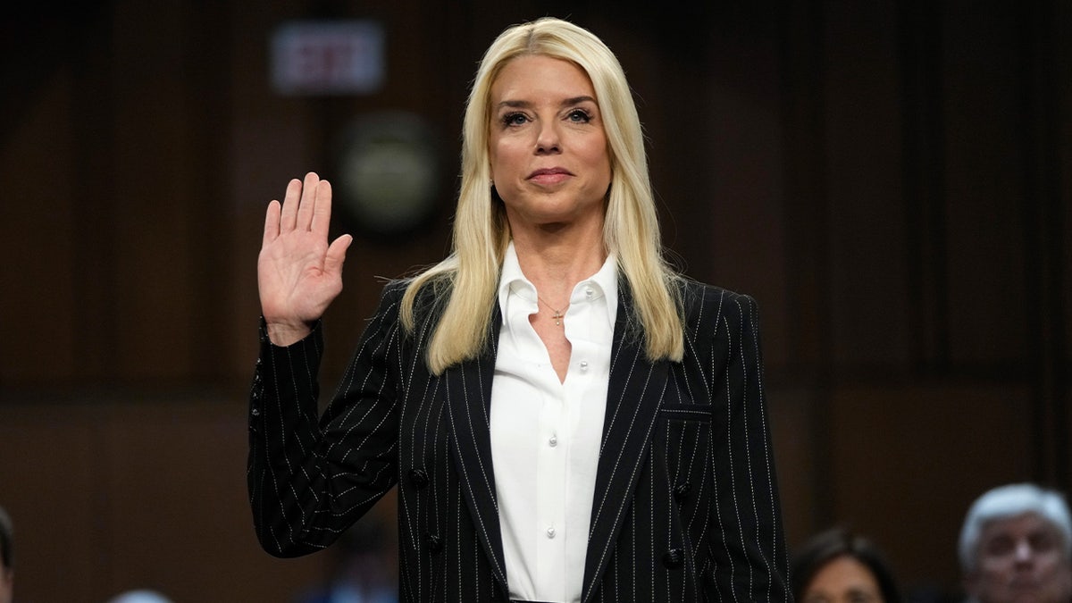 Pam Bondi with her right hand raised