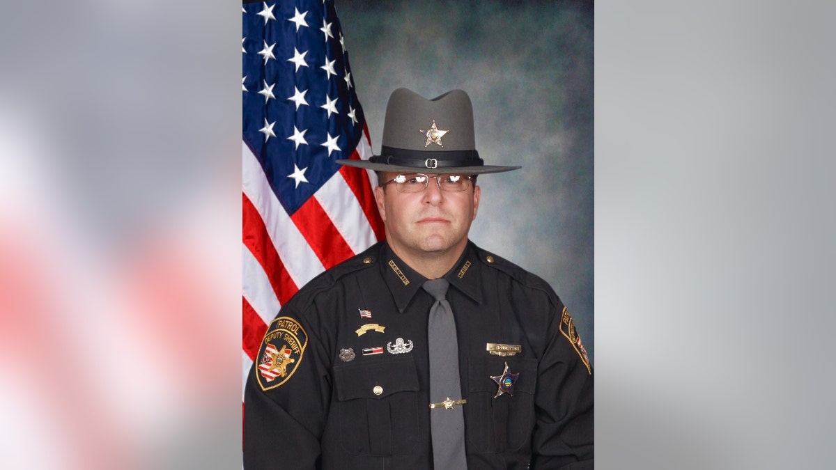 Hamilton County Deputy Larry Henderson posing for photo with an American flag in background