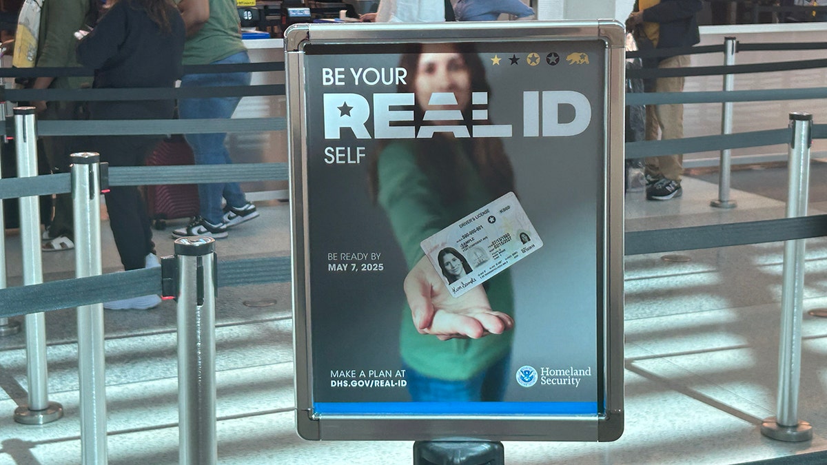 A sign at an airport of a woman holding out her "REAL ID" to encourage travelers to get their REAL ID done before the travel ban takes place.