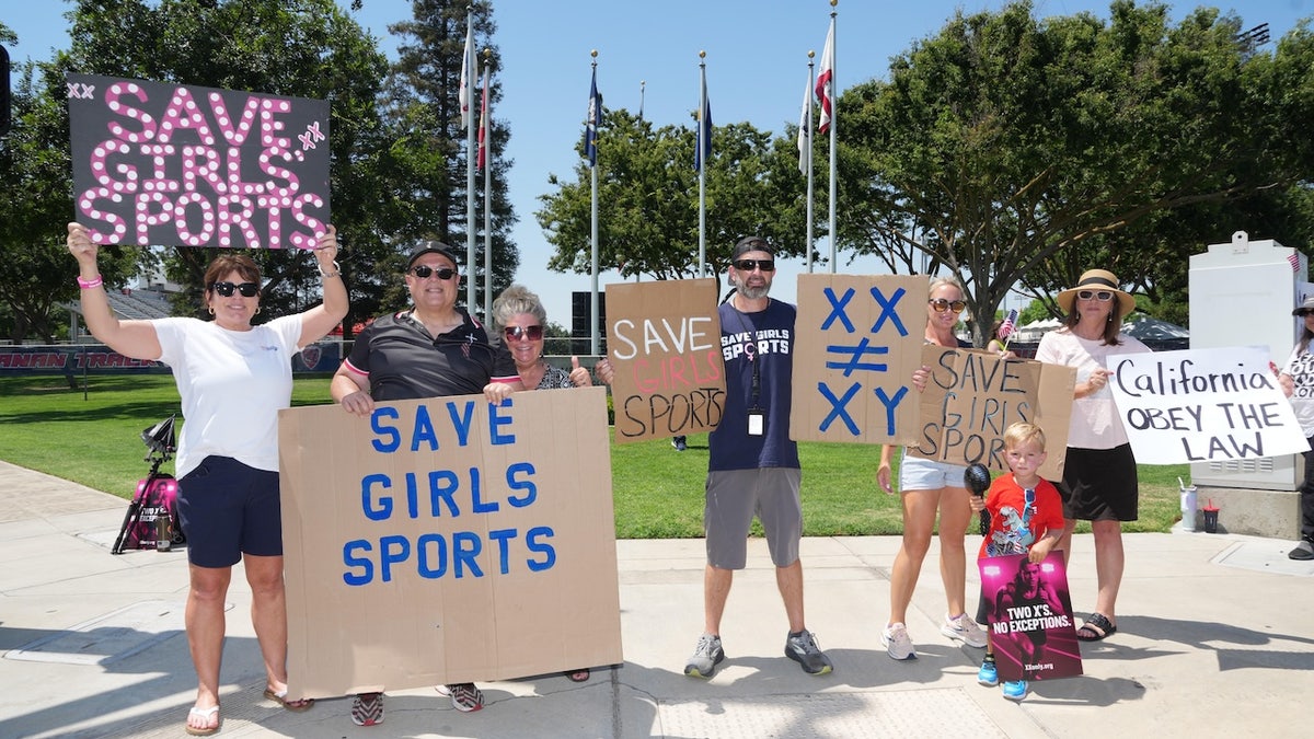 People hold Save Girls Sports signs in protest of transgender athlete AB Hernandez of Jurupa Valley (not pictured) during the CIF State Track and Field Championships at Veterans Memorial Stadium on May 30, 2025 in Clovis, California. 