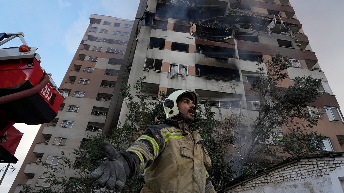 A firefighter standing under a damaged building in Tehran, Iran following airstrikes by Israel.