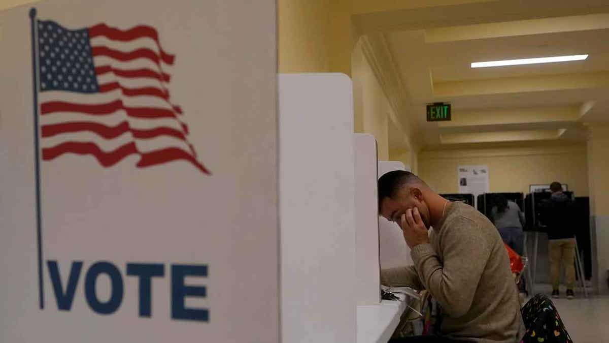 man voting, us flag, VOTE sign at left of photo
