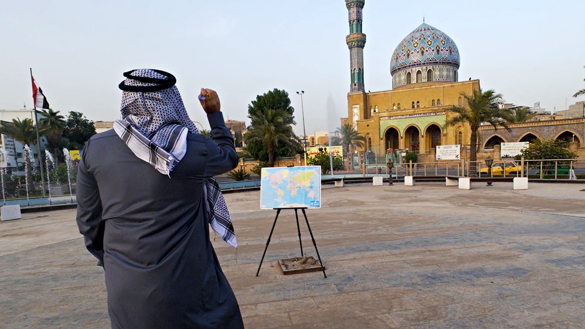 Sorin Mihailovici throwing a dart in Iraq. A man has travelled to over 60 countries by throwing a dart a world map and visiting where ever it lands.