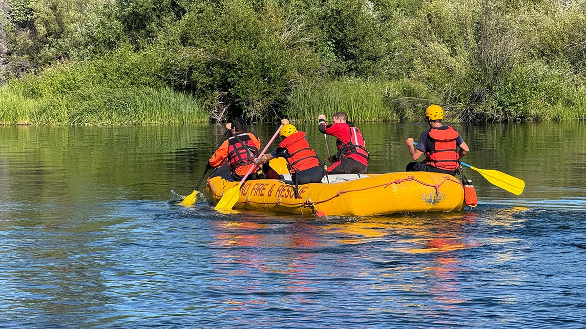 search team paddling yellow raft along river