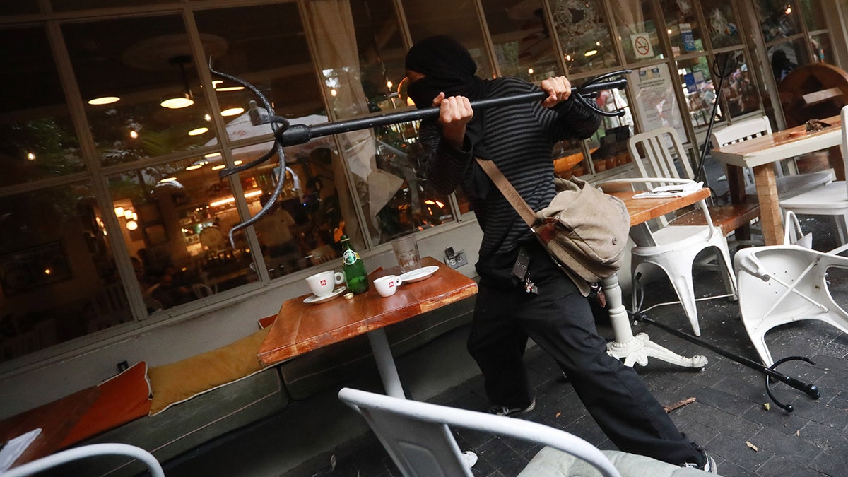 MEXICO CITY, MEXICO - JULY 04: Demonstrator throws objects at a restaurant during the first anti-gentrification protest, in Mexico City, Mexico on July 04, 2025. People gathered to take part in the first anti-gentrification demonstration to protest against its social and economic negative impact as displacement of residents, an increase of cost of living and accommodation costs for locals caused by the influx of foreign people living in the country. (Photo by Daniel Cardenas/Anadolu via Getty Images)