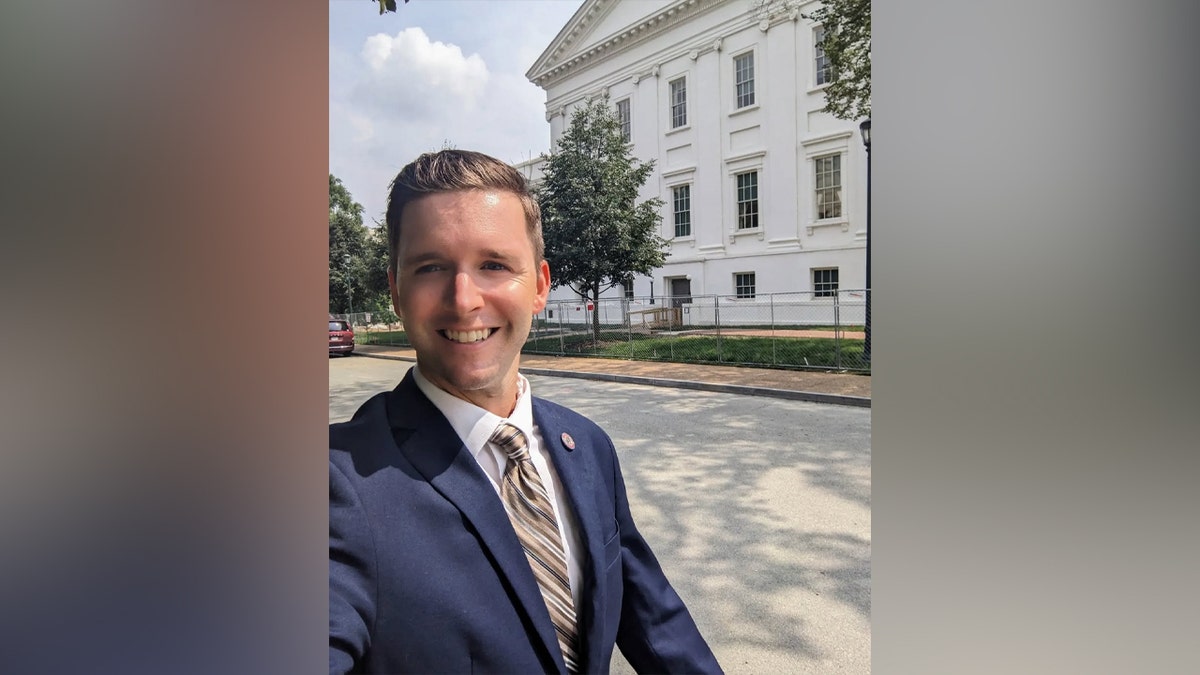 Lee Vogler smiles for selfie with a building