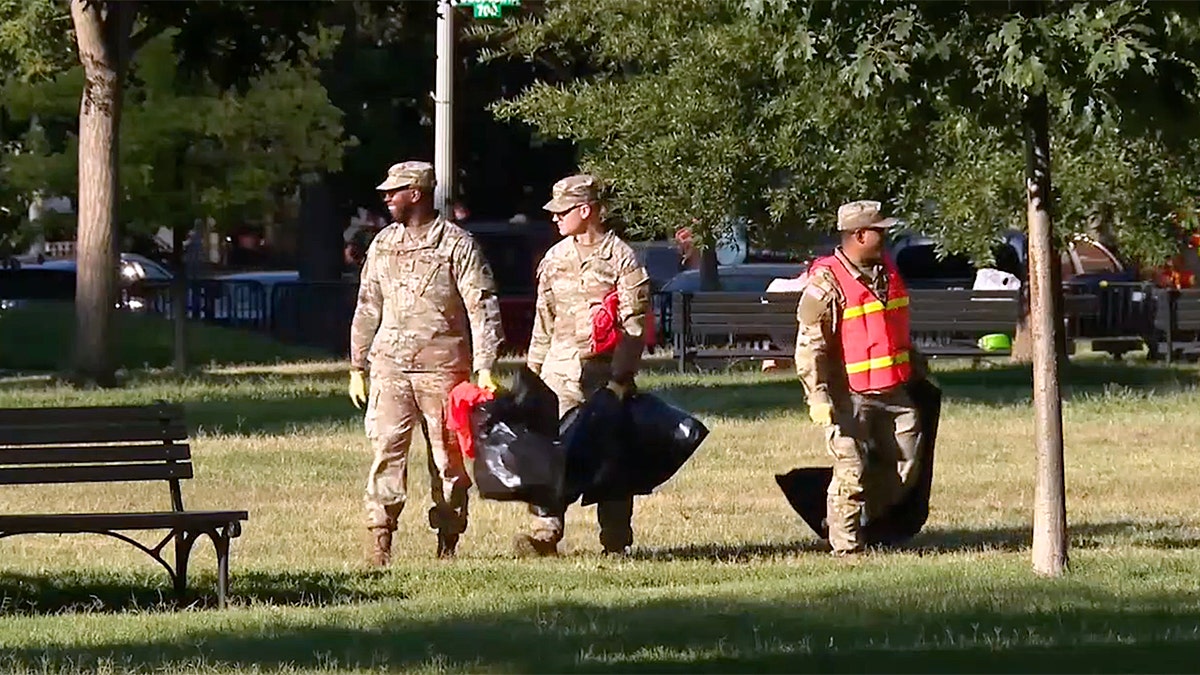 ational Guard troops in uniform carry trash bags while cleaning Lafayette Park in Washington
