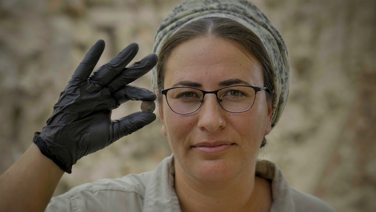 Female archaeologist holding coin