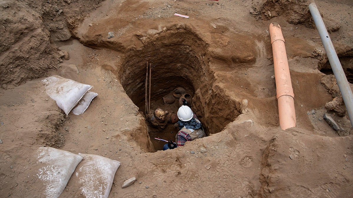 Wide shot of worker working in trench with skeleton