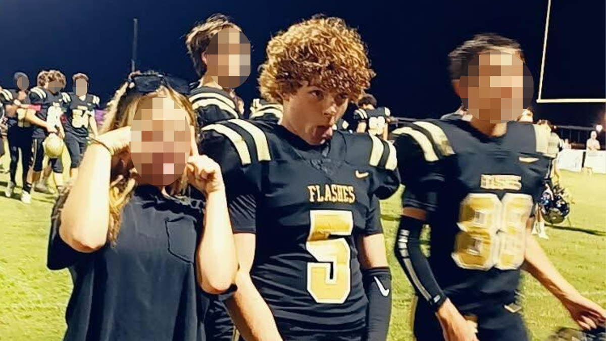 Trey Wright, in his football uniform on the field, flanked by friends as they celebrate after a game