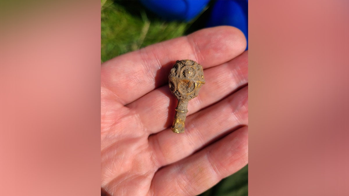 Hand holding ancient golden artifact