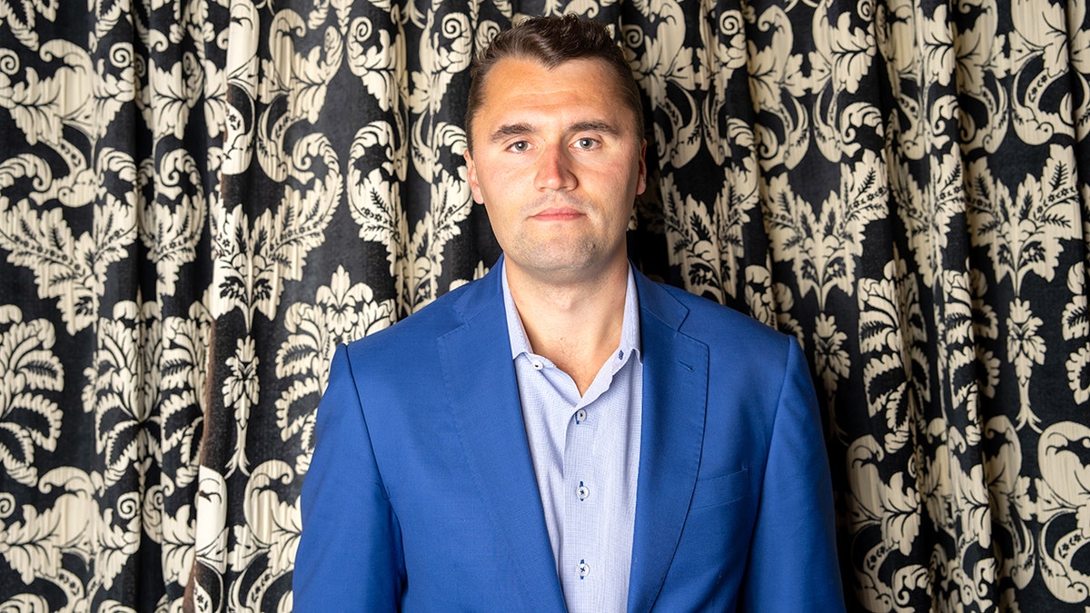 Charlie Kirk in front of a curtain
