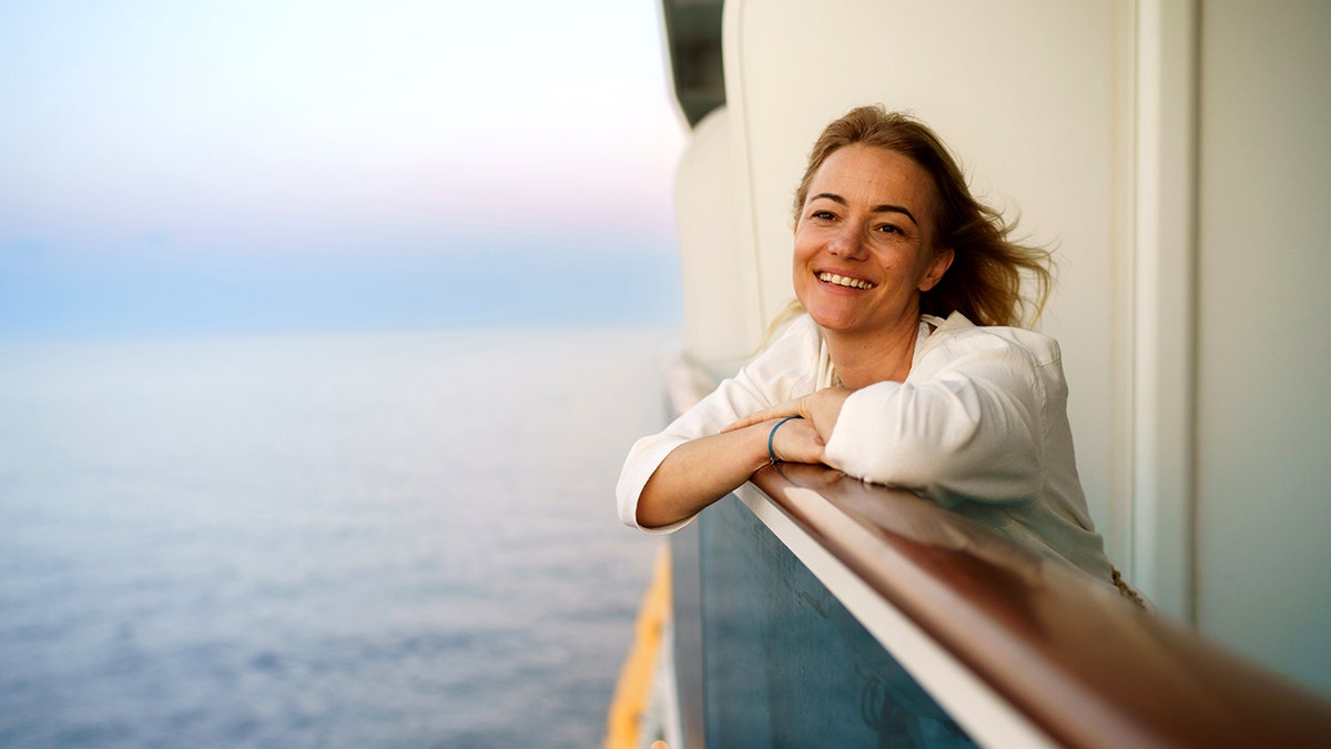 A smiling woman on the balcony of a cruise ship