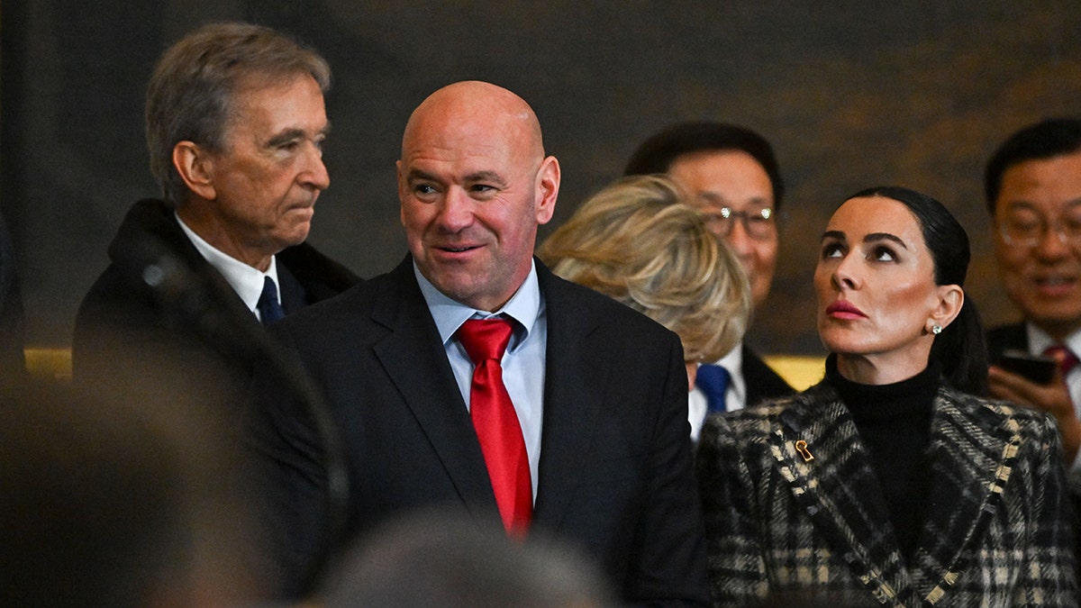 Dana White in a black suit and red tie arrives at the Rotunda with his wife Anne