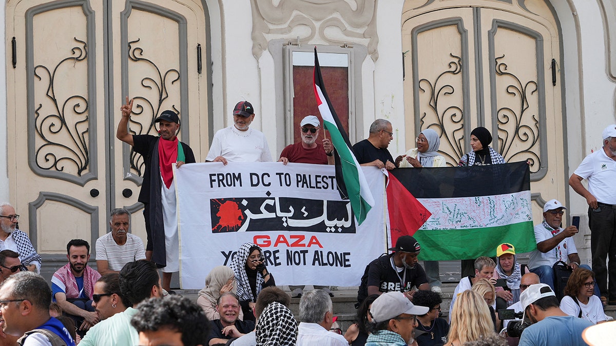 People hold a banner and Palestinian flags at group's press conference