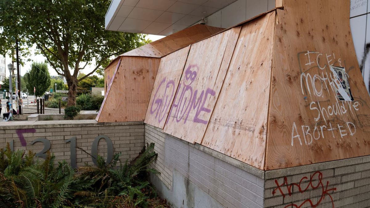 Boarded windows with graffiti at Portland ICE facility.