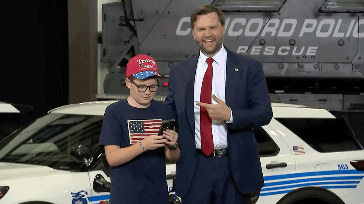 A boy in an American flag shirt takes a photo with Vice President JD Vance during a speech in Concord, North Carolina.