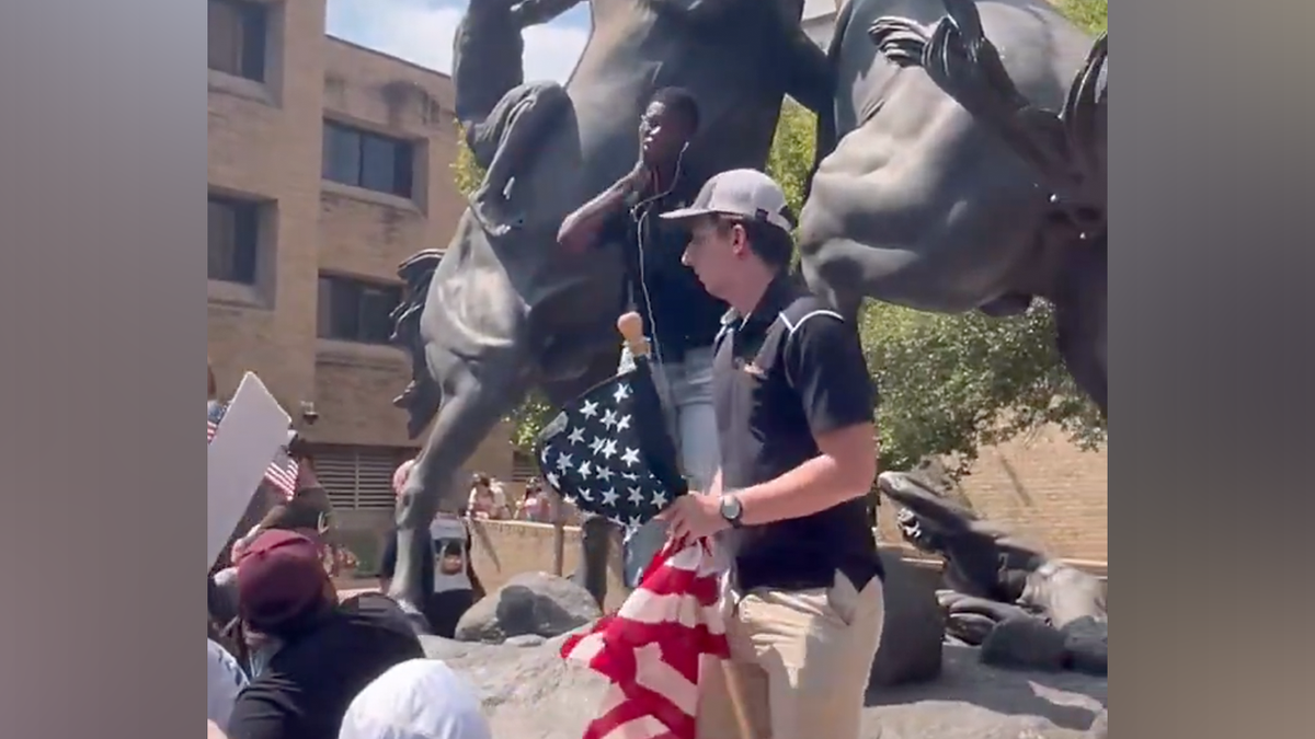 The man acted out the assassination in front of a statue, as the crowd gasped.