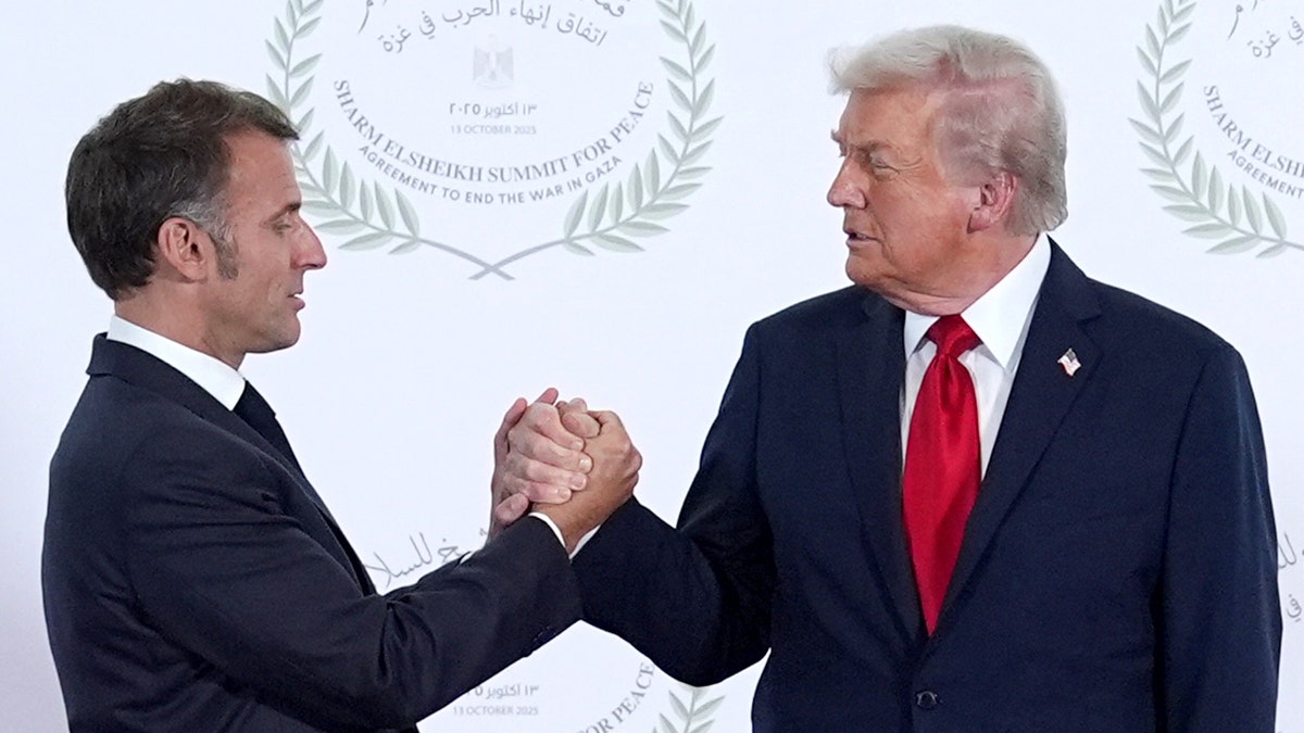 French President Emmanuel Macron clasps hands with U.S. President Donald Trump