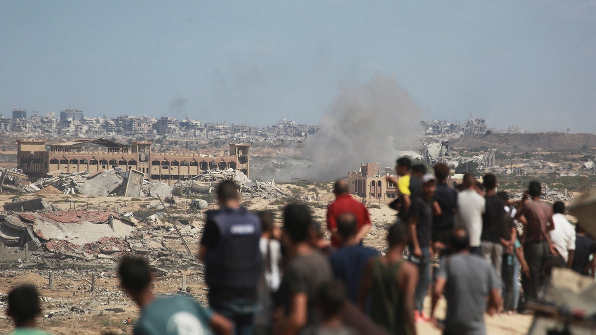 Palestinians watch smoke billowing during Israeli strikes