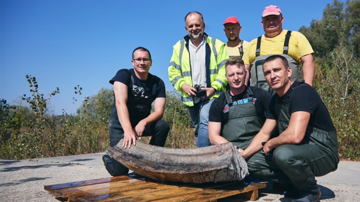 Smiling archaeologists next to recovered artifacts