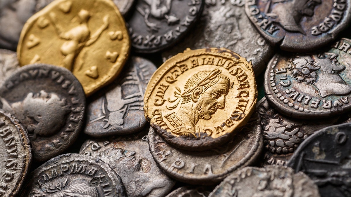 Ancient Roman coins in silver and gold with detailed engravings of faces and symbols.