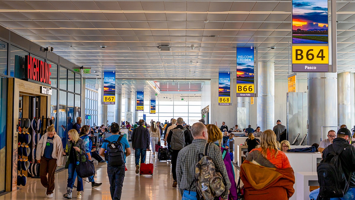 People walking through terminal at Denver airport with suitcases
