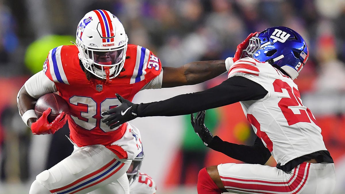 Rhamondre Stevenson stiff arms a defender