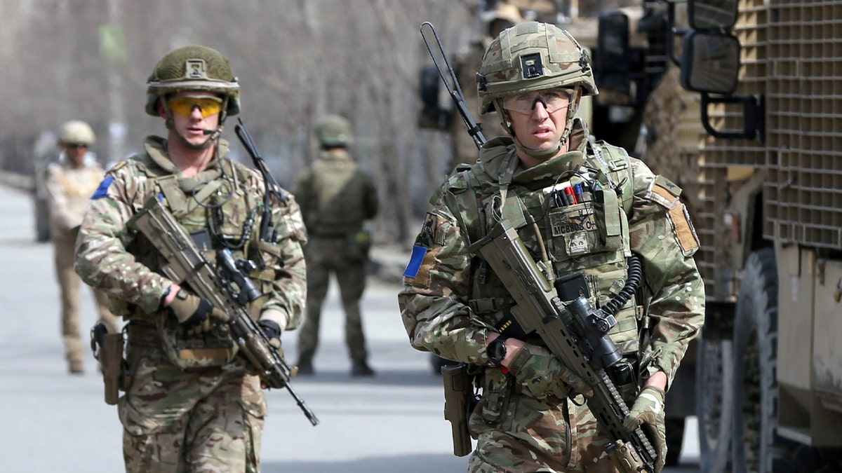 British soldiers in military gear move through a secured area following an attack.
