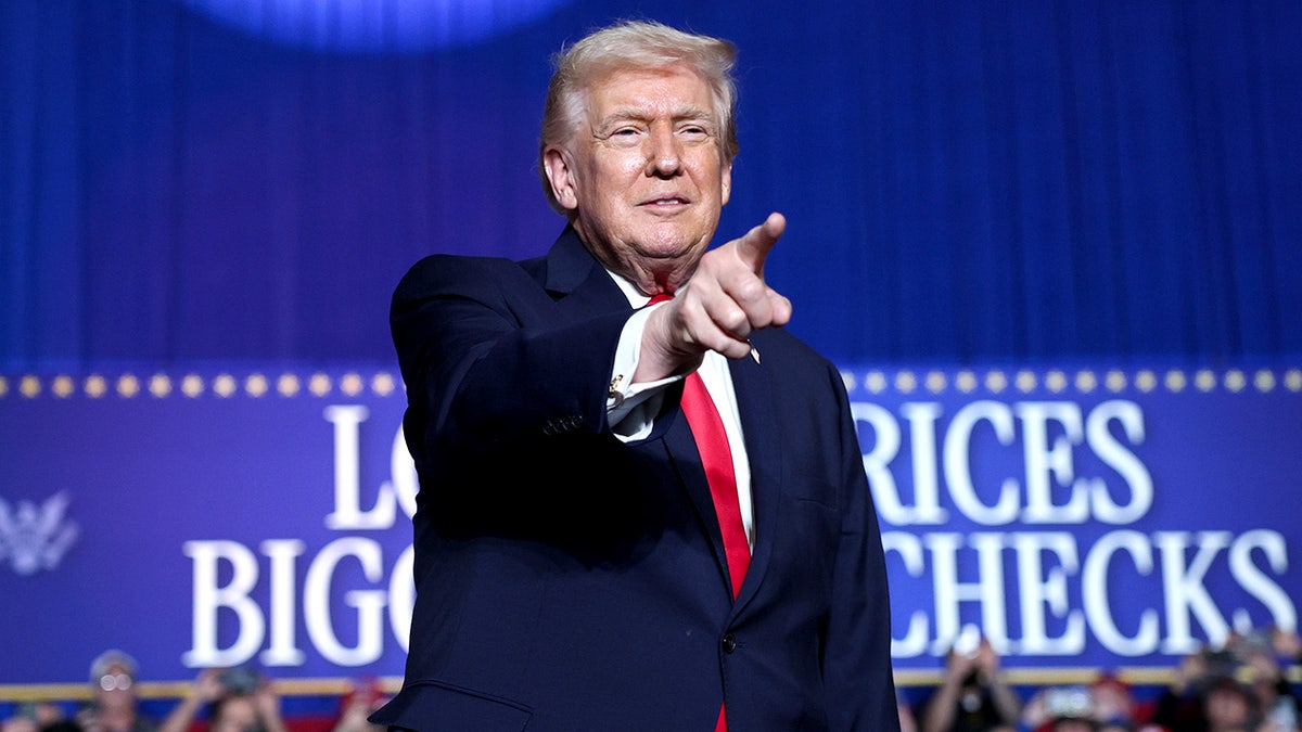 Donald Trump stands at a podium while speaking to a crowd at an indoor rally.