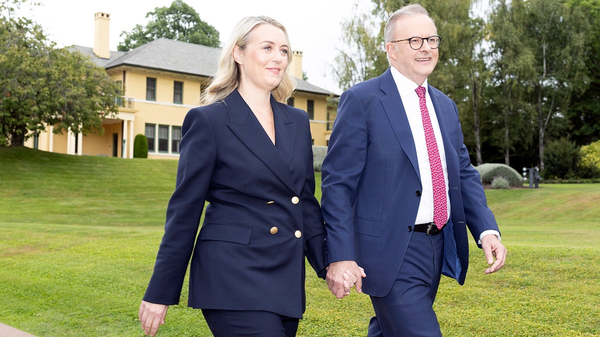 Anthony Albanese and Jodie Haydon hold hands while walking in Canberra, Australia