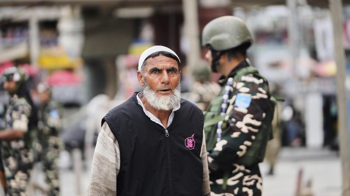 Indian soldiers stand guard as a Kashmiri Muslim man walks by,  in Srinagar, Indian-controlled Kashmir, Friday, May 9, 2025.