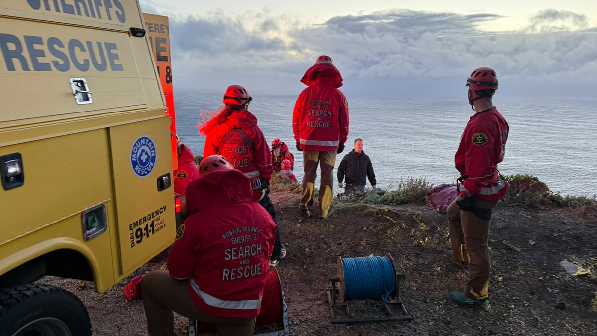 Monterey County Sheriff’s Search and Rescue members stand near a cliff above the Pacific Ocean during recovery efforts in Big Sur.