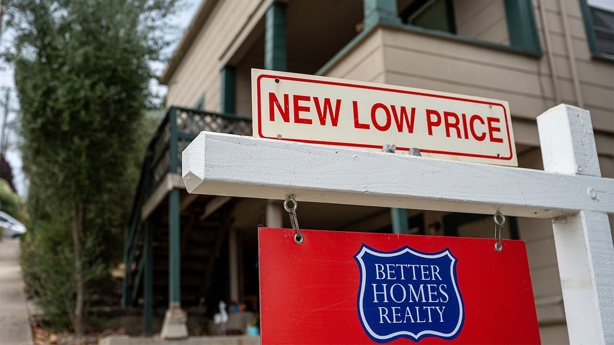 A for sale sign on a home advertising a lower price