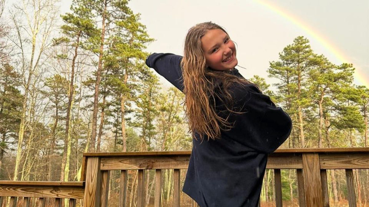 Madelyn Eitas posing in front a rainbow.