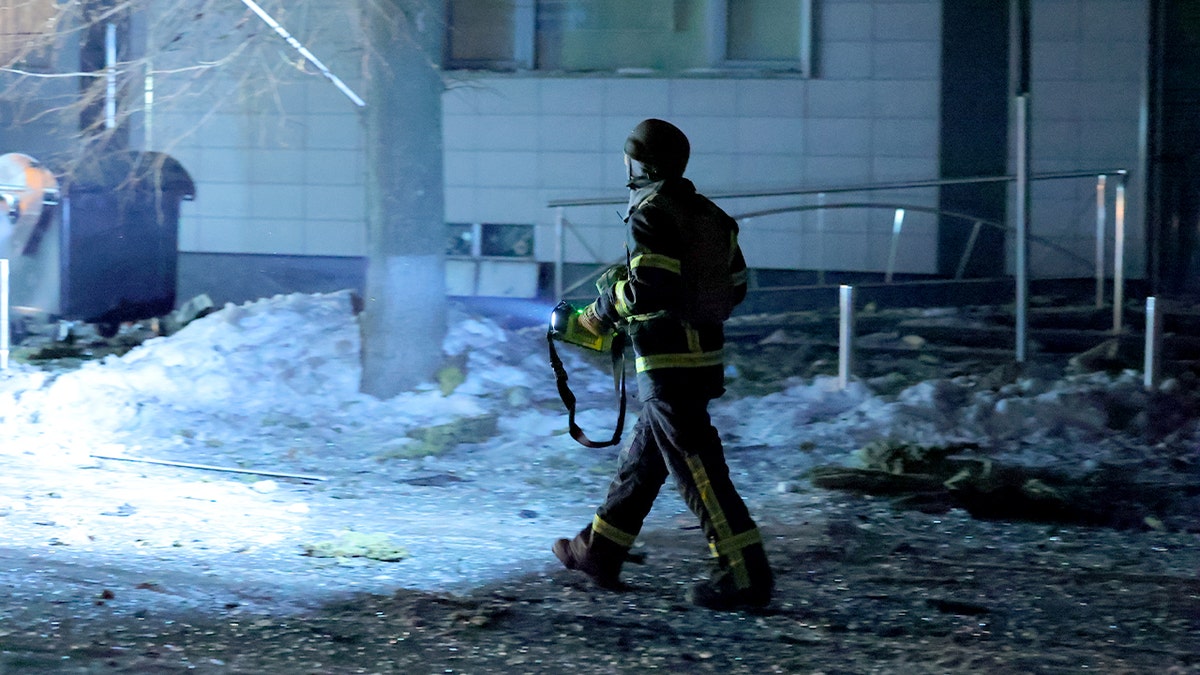 Emergency worker walks at night in the snow.