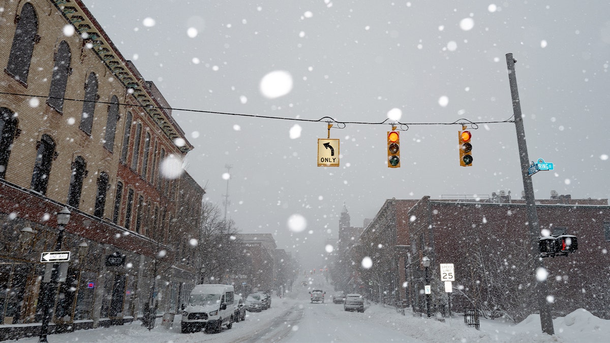 A snow-covered city street in Marquette, Michigan, with traffic lights and falling snow.