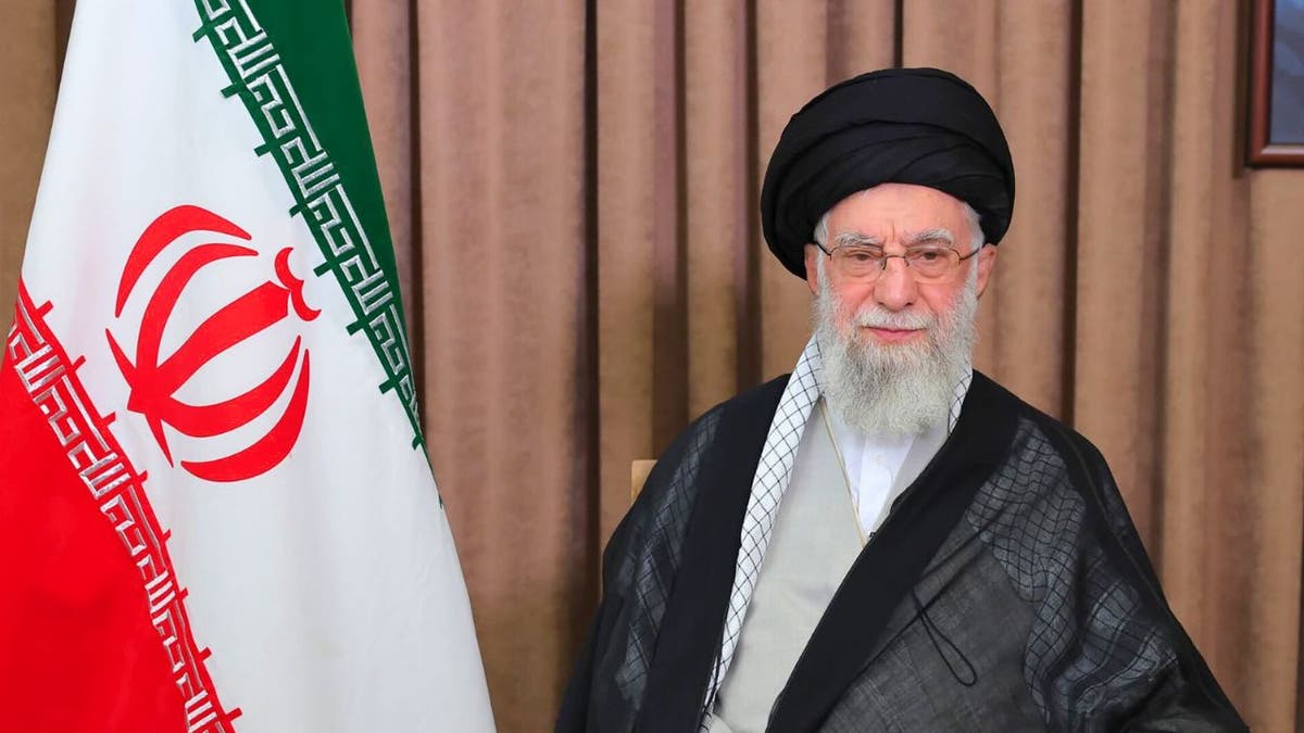 Iranian Supreme Leader Ali Khamenei seated beside the Iranian flag during an address.