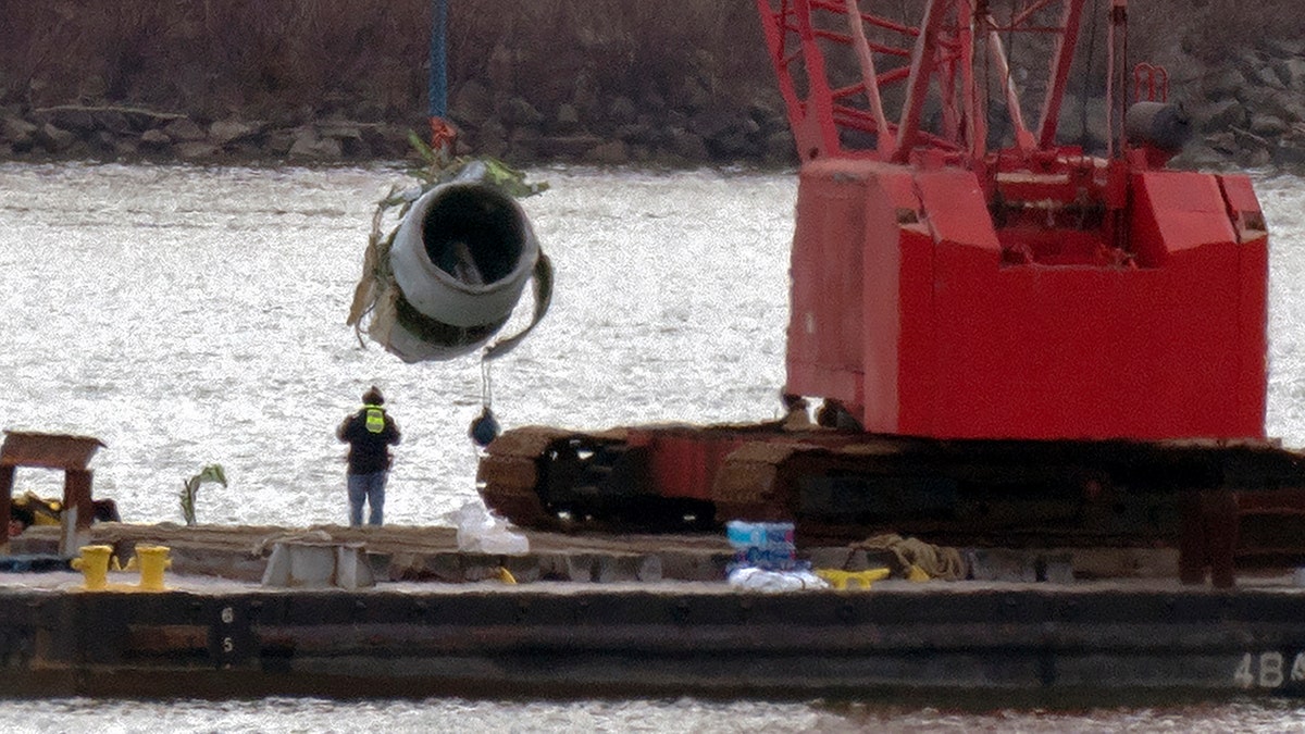 Rescue and salvage crews pull up a plane engine as cranes work near the wreckage of an American Airlines jet in the Potomac river from Ronald Reagan Washington National Airport, on Monday, Feb. 3, in Arlington, Va.