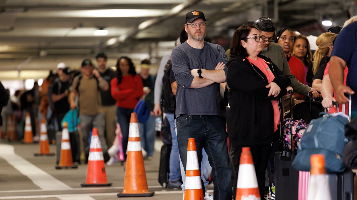 Flight passengers wait in TSA line in parking lot at Houston Airport.