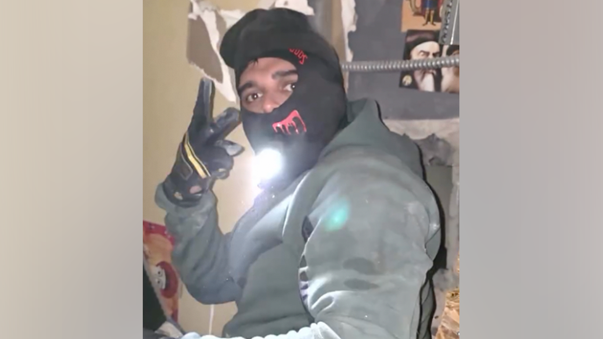 Masked burglary suspect flashes a peace sign while holding a flashlight inside a Simi Valley jewelry store during a $3 million heist, according to prosecutors