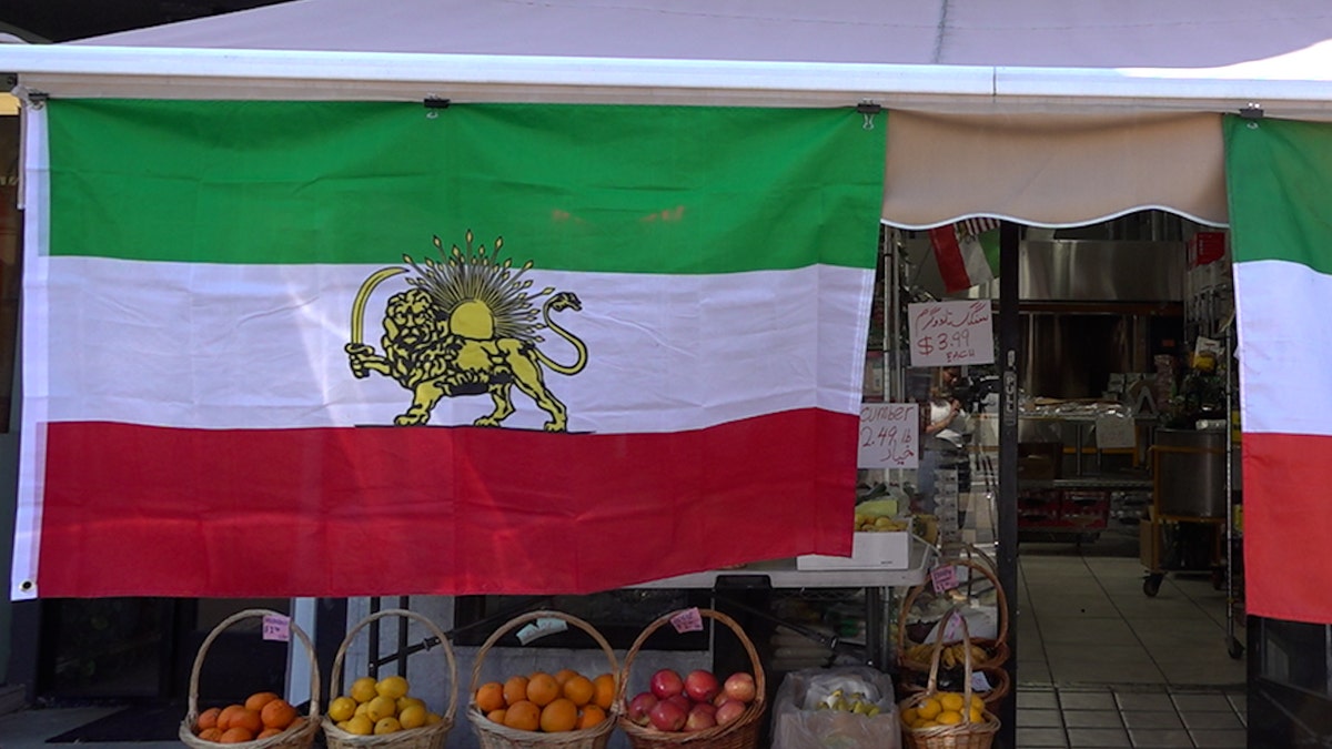 The old Iranian flag hangs from a grocery store awning.